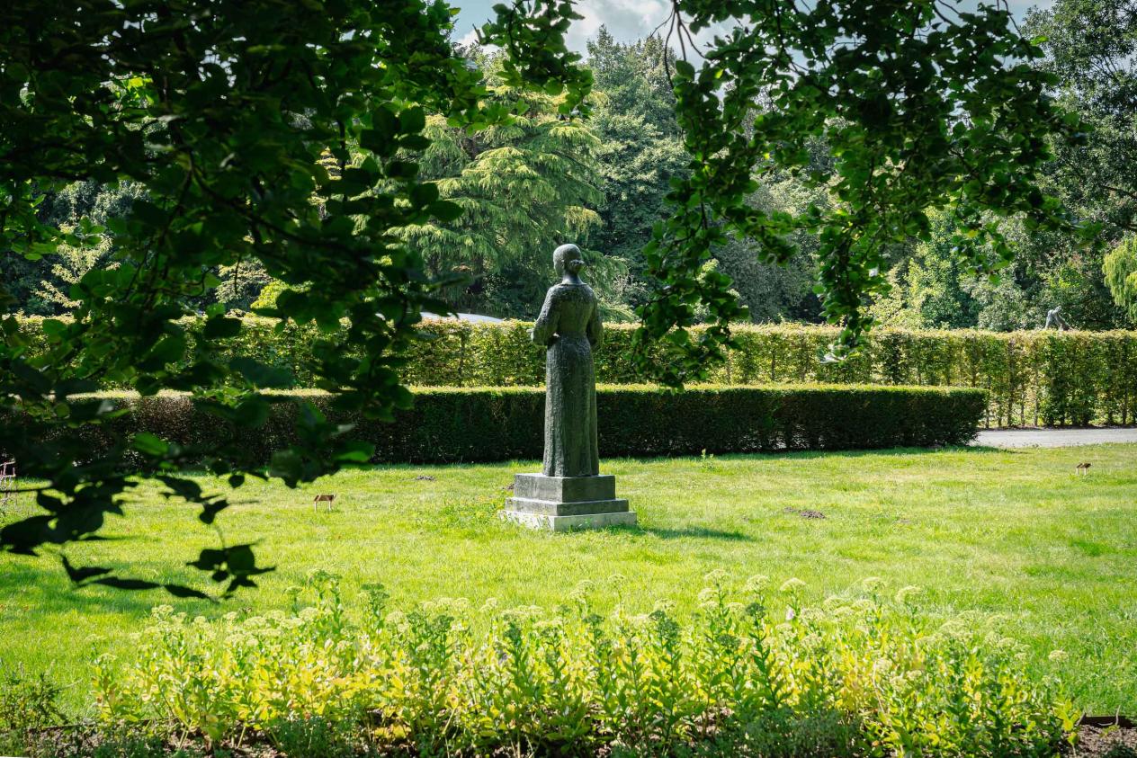 Achteraanzicht van standbeeld Anna Ancher te midden van een groene parkomgeving