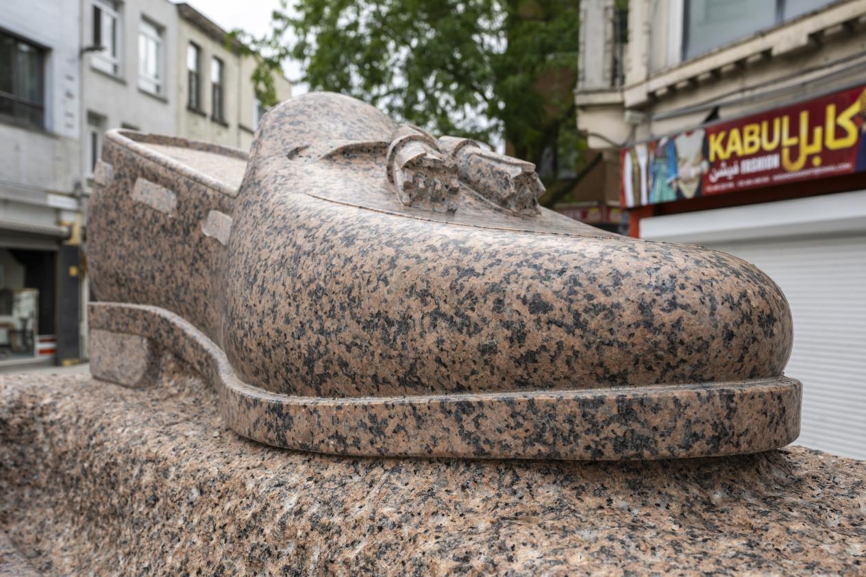 Loafer met kwastjes, gehouwen uit roze granieten rots, deel van kunstwerk