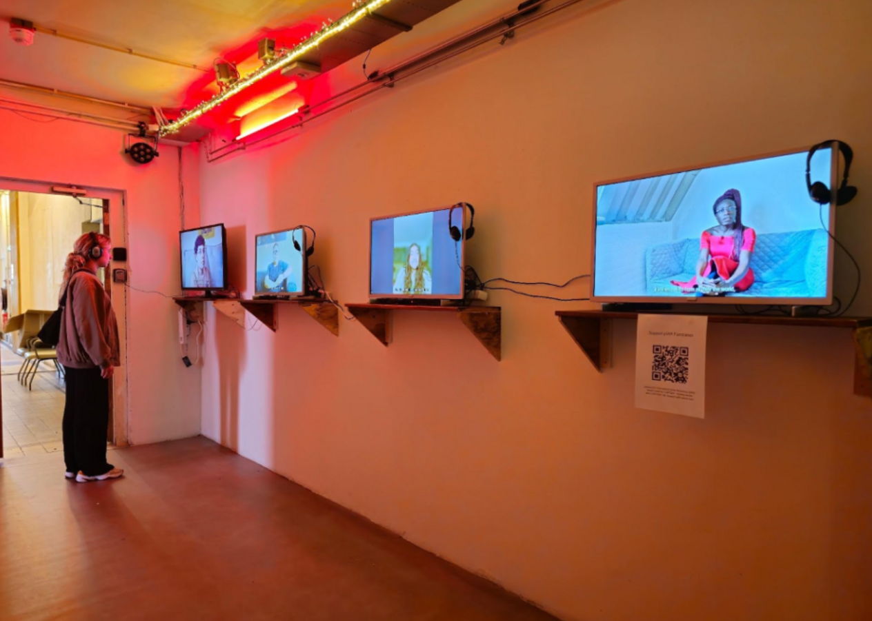 Sfeerbeeld Viva La Vulva Festival at 0T301: jonge persoon bekijkt met koptelefoon een van de vier opgestelde televisieschermen in expo
