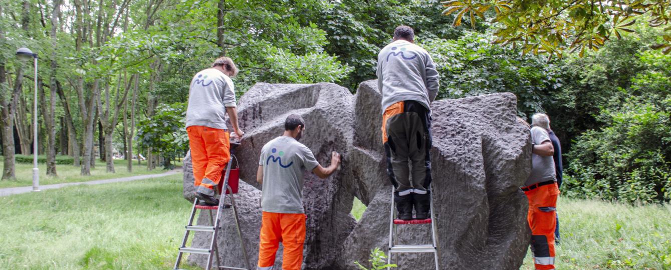 Medewerkers restaureren een werk in het kunstpark 