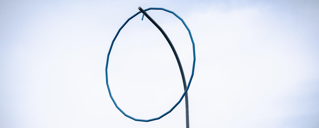 Detail kunstwerk met blauwe ring op hoge paal 