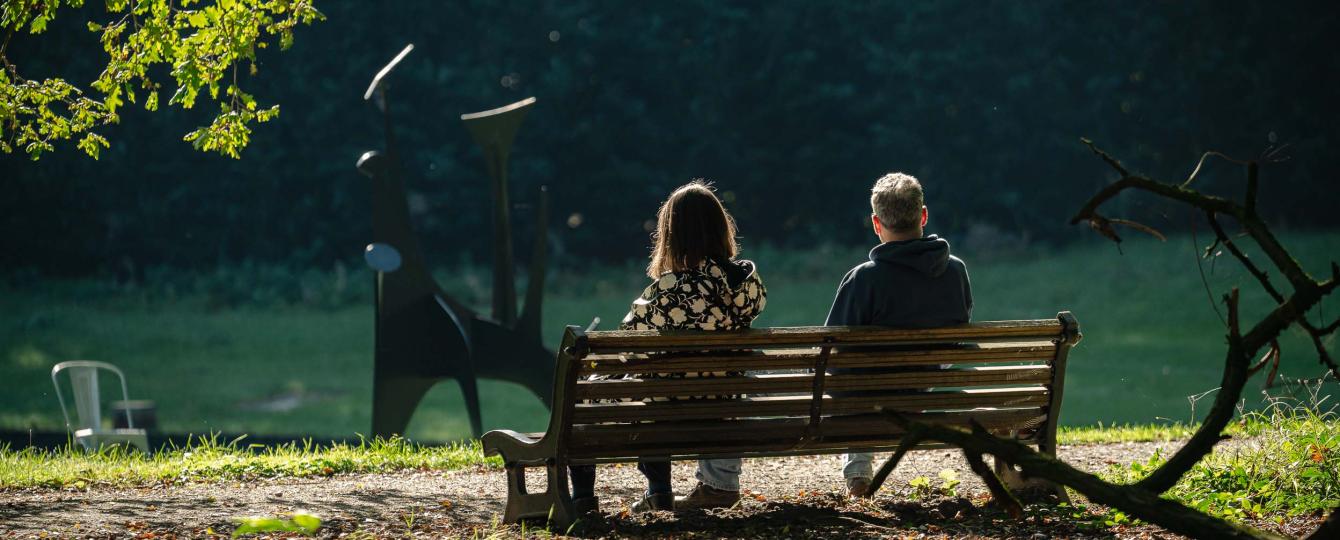 Achteraanzicht van man en vrouw op houten zitbank in het kunstpark