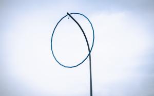 Detail kunstwerk met blauwe ring op hoge paal 