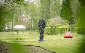 Zicht vanuit gebladerte op Hortiflora met kunstwerk van Deacon, Creten en Visch