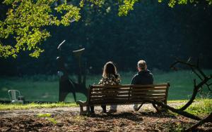 Achteraanzicht van man en vrouw op houten zitbank in het kunstpark