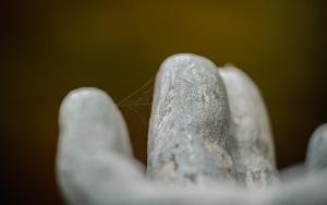 Herfstig sfeerbeeld van detail vingers standbeeld met draden spinnenweb ertussen