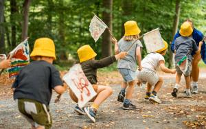 Kleine kinderen met gele hoedjes en zwaaiend met vlaggetjes stappend achter elkaar in het kunstpark