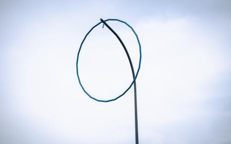 Detail kunstwerk met blauwe ring op hoge paal 