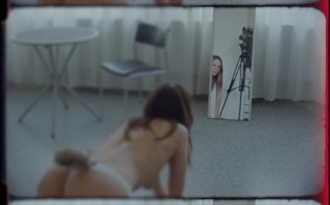 Filmstill waarin een mysterieus, geslachtshybride wezen (half mens, half lynx) in een spiegel kijkt