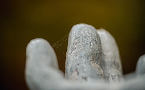 Herfstig sfeerbeeld van detail vingers standbeeld met draden spinnenweb ertussen