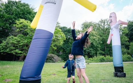 Jongen en meisje springen naar een van de skytubes uit het kunstwerk The Pogo Never Stops van Dennis Tyfus, opgesteld in het kunstpark van het Middelheimmuseum.