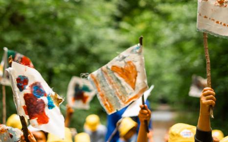 Detailzicht sfeerbeeld van kinderhanden wapperend met kleurrijke vlaggetjes 
