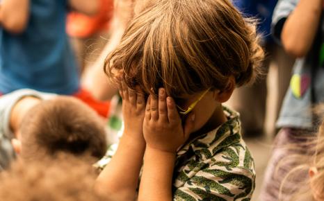 Sfeerbeeld van spelend jong kind met handen voor gezicht