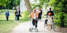 Erfgoedbewaker met fluohesje voert performance Le Tag van Joëlle Tuerlinckx uit en trekt een witte krijtlijn door het kunstpark terwijl bezoekers hem passeren.