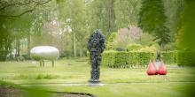 Zicht vanuit gebladerte op Hortiflora met kunstwerk van Deacon, Creten en Visch