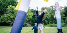 Jongen en meisje springen naar een van de skytubes uit het kunstwerk The Pogo Never Stops van Dennis Tyfus, opgesteld in het kunstpark van het Middelheimmuseum.