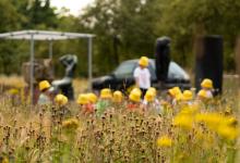 Zicht op kinderen met gele zonnehoedjes en begeleider in het grasveld van het openluchtdepot van het Middelheimmuseum