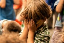 Sfeerbeeld van spelend jong kind met handen voor gezicht